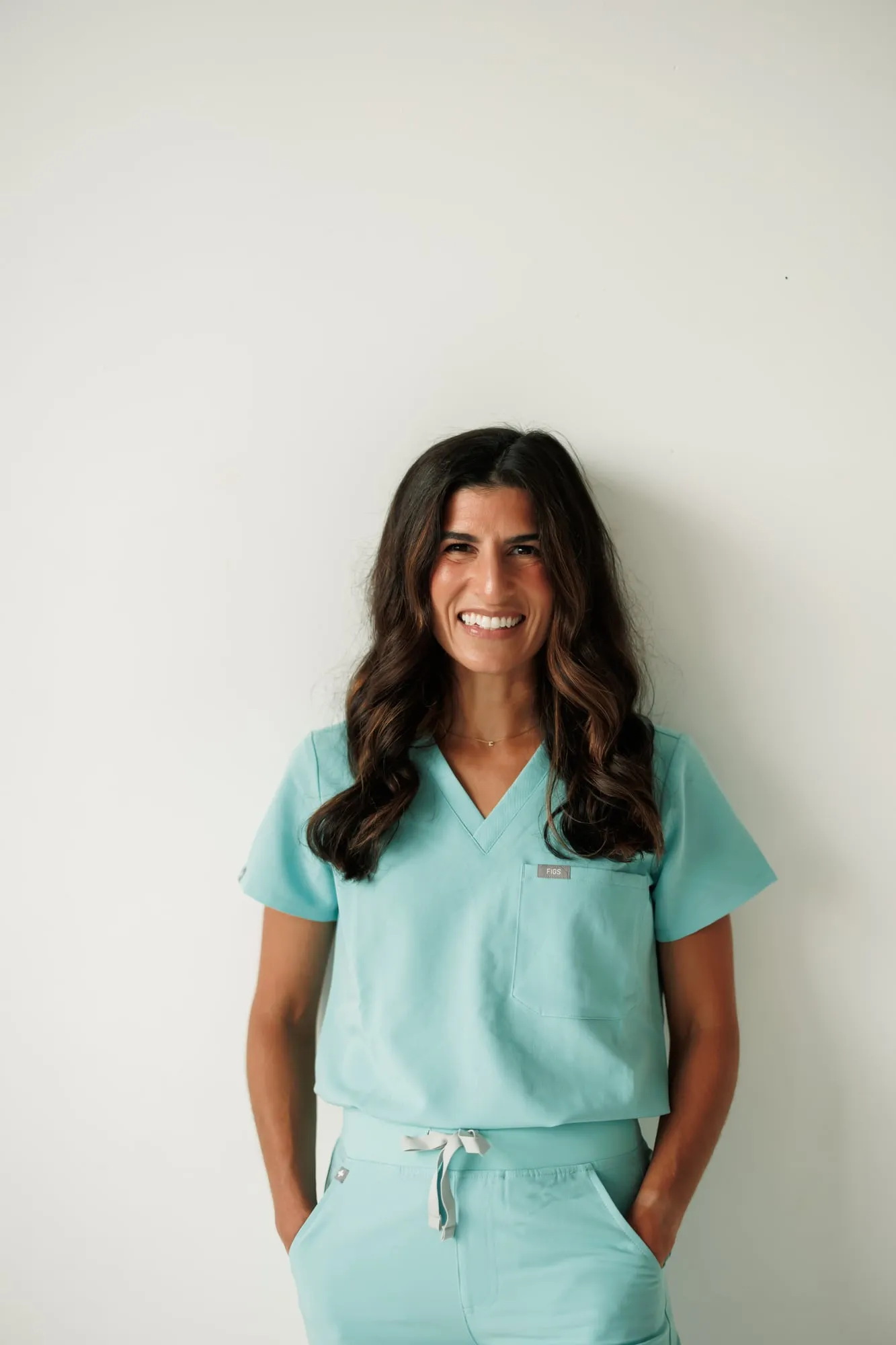 Dr. Caris Miller standing in sky-blue scrubs with her hands in her pockets